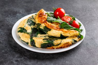 Beyaz tabakta ıspanaklı omlet ve marullu domates, sabah kahvaltısı.