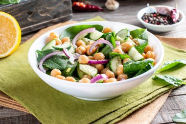 Bir tabakta nohut, ıspanak, salatalık, soğan ve yeşillik salatası. Beslenme yemeği. Vegan salatası.