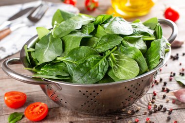 Natural organic fresh spinach in a metal sieve on a wooden table