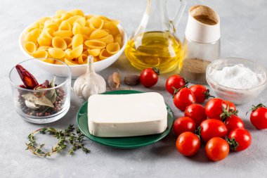 Preparation of ingredients for feta pasta. Trending Feta bake pasta recipe made of cherry tomatoes, feta cheese, garlic and herbs on a background.