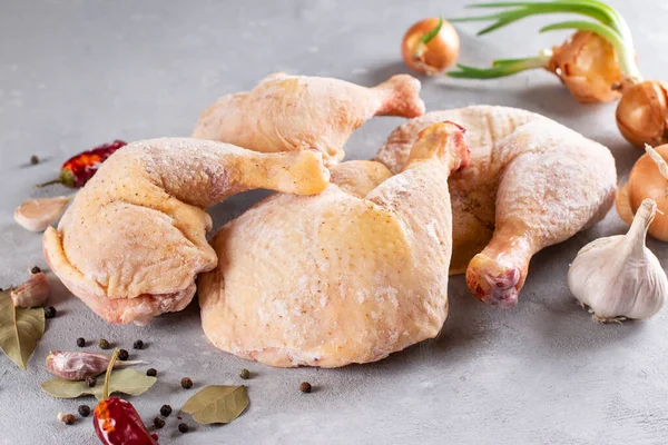 Frozen meat. Frozen chicken legs on a light concrete background. Raw chicken meat.