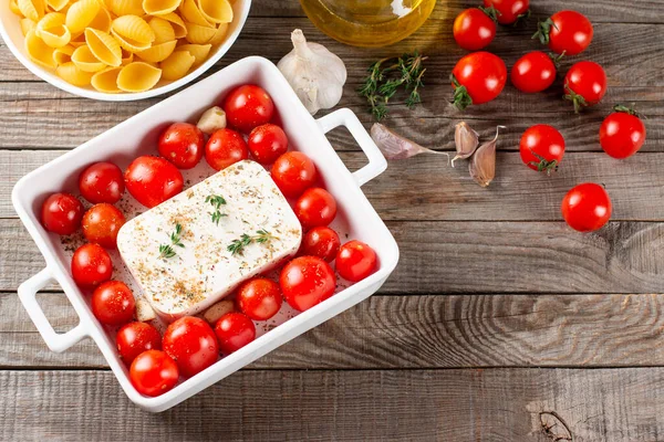 Preparation of ingredients for feta pasta. Trending Feta bake pasta recipe made of cherry tomatoes, feta cheese, garlic and herbs. Top view, above, copy space.