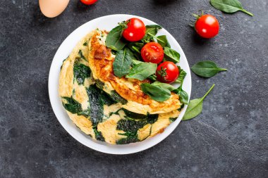 Beyaz tabakta ıspanaklı, domatesli ve baharatlı yeşil omlet. Frittata - İtalyan omleti. Üst görünüm.