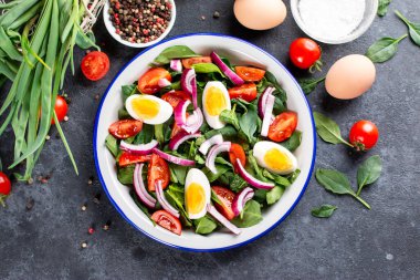 Taze ıspanak, haşlanmış yumurta, domates, fındık ve baharattan oluşan lezzetli bir salata. Yukarıdan görüntüle.