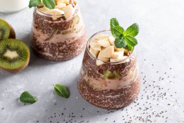 Chia tohumlu çikolatalı puding, kivi ve muzlu gri masada. Süper yemek.