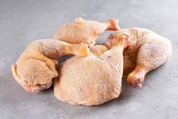 Frozen meat. Frozen chicken legs on a light concrete background. Raw chicken meat.