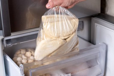 Buzdolabında dondurulmuş börek. Donmuş hamur köftesi, bir tabak hamur ve un. Buzdolabında bir sürü börek var. Donmuş yarı bitmiş ürünler