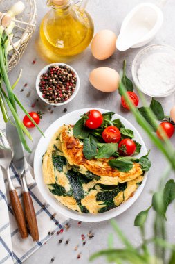 Beyaz tabakta ıspanaklı omlet ve marullu domates, sabah kahvaltısı.