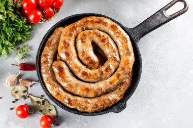 Baharatlı ve otlu ızgara sarmal sosis ve taştan bir arka planda kızartma tavası. Yukarıdan görünüm al ve boşluğu kopyala