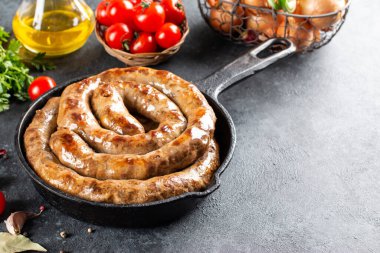 Baharatlı ve otlu ızgara sosis, taştan bir arka planda kızartma tavasında, boşluğu kopyala.