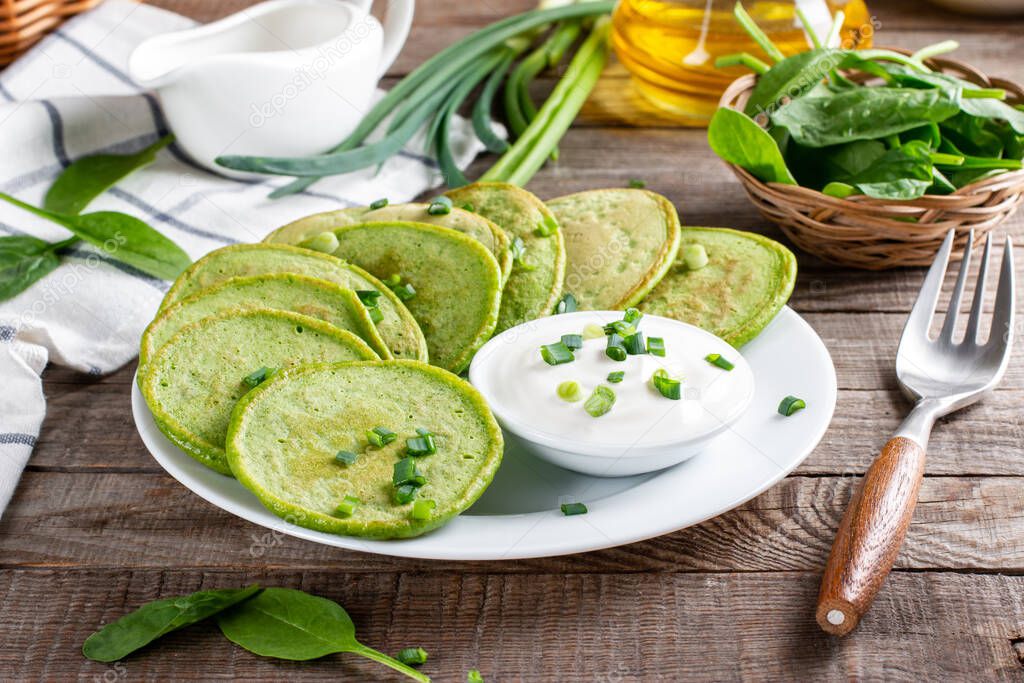 Pancakes with spinach and sour cream on a wooden table. Gluten free spinach pancakes recipe