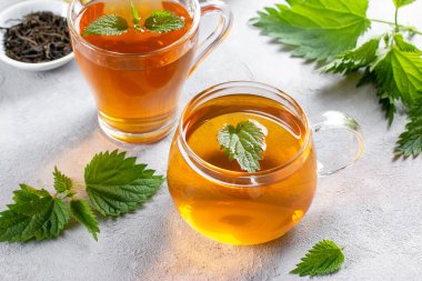 Isırgan otu çayı, içinde taze ısırgan otu olan bir bardakta, masada. Halka açık tedavi. Vitaminlerin kaynağı.