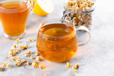 Masada papatya çayı, şeffaf bardakta sıcak aromalı içecek, rahatlama ve detoks.