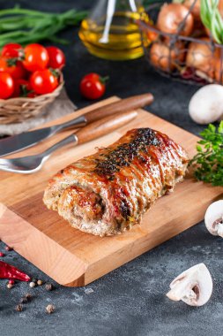 Mantarla doldurulmuş domuz eti ruloları ve ahşap bir tahtanın üzerinde sebzelerle servis edilen peynir.