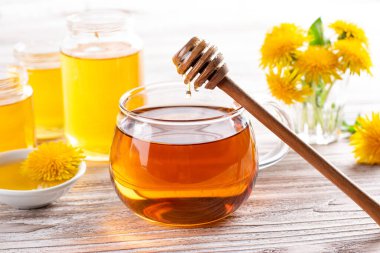 Taze karahindiba yaprağının bitki çayı karışımı, sarı çiçekler ve beyaz ahşap masa üzerinde bal..