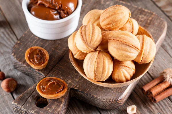 Ev yapımı kurabiyeler fındık şeklinde ve ahşap masada kaynatılmış konsantre süt. Kırsal biçim