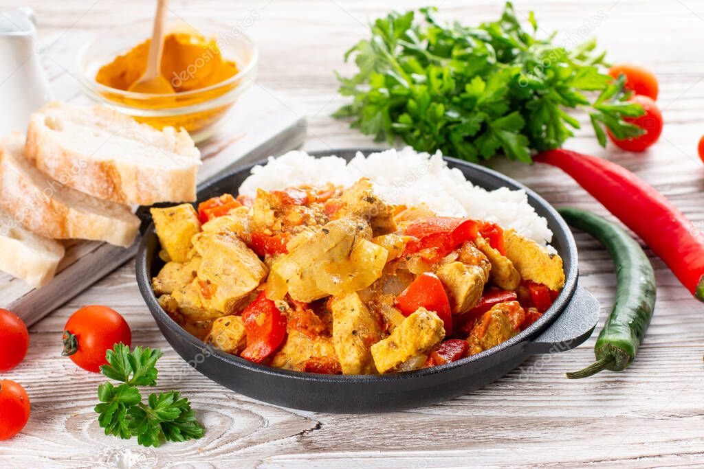 Indian chicken curry or kadai chicken with rice in a frying pan on a wooden table