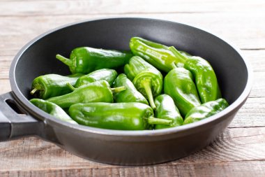 Taze yeşil pimientolar ya da kızartma tavasında biber de padron. Zeytinyağında kızartılmış ve üzerine deniz tuzu serpiştirilmiş İspanya 'da tipik bir tapa yemeğidir. seçili odak, alanın dar derinliği