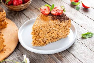 Tahta bir masanın üzerinde yoğunlaştırılmış süt, çikolata ve çilekli iştah açıcı waffle keki.