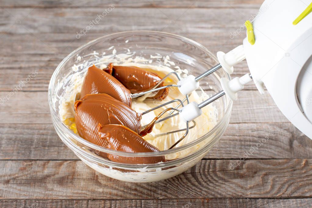 Butter and boiled condensed milk in a glass bowl with a mixer. Making cake cream