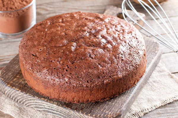 Homemade round chocolate sponge cake or chiffon cake so soft and delicious with ingredients: eggs, flour, cocoa, milk on wood table. Homemade bakery concept for background and wallpaper