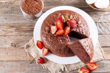 Yuvarlak fırında çikolatalı kek ve ahşap masada çilek. Boşluğu kopyala