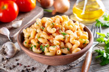 Vejetaryen sebze makarnası, domates ve sebzeler ahşap bir masada kasede..