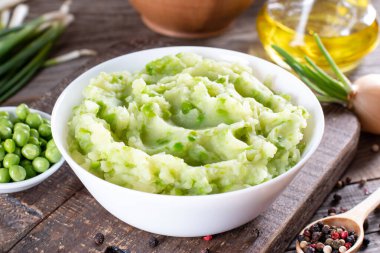 Mashed green peas and potatoes in a bowl on a wooden table clipart