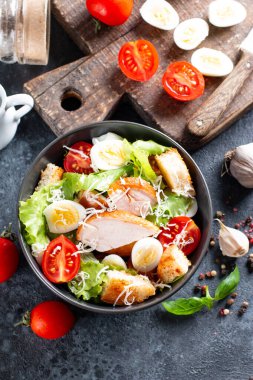 Sezar salatası, füme tavuk ve koyu arkaplanda parmesan. Üst görünüm