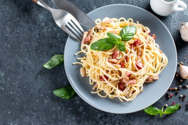 Gri masadaki Carbonara spagettisi. Ev yapımı pastırmalı makarna, yumurta, parmesan peyniri ve krem soslu. Geleneksel İtalyan mutfağı. Üst görünüm, alanı kopyala.