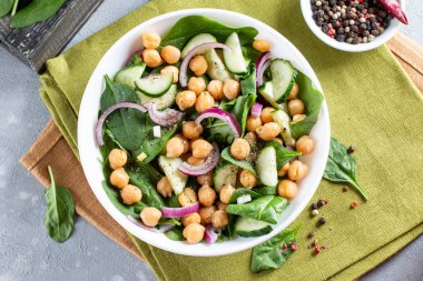 Hafif arkaplanda ıspanak, salatalık, nohut, soğan ve limon salatası. Üst görünüm