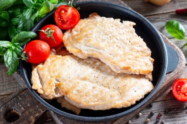 Kızarmış tavuk pirzolası. Tahta masada domatesli kızarmış tavuk pirzolası. Kırsal tarzda. Yakın çekim..