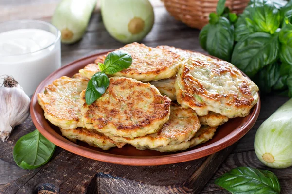 Zucchini pancakes with parsley on a wooden table