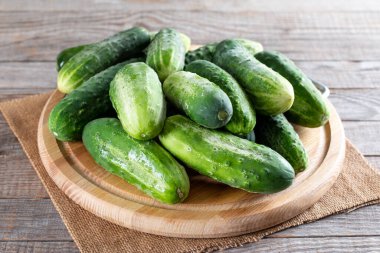 Tahta bir masanın üzerindeki kesme tahtasındaki taze yeşil salatalıklar. Sağlıklı vejetaryen malzemesi