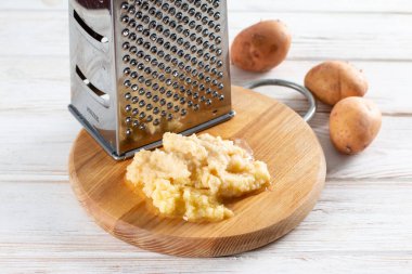 Ahşap masa üzerinde metal rendesi olan ızgara patates.