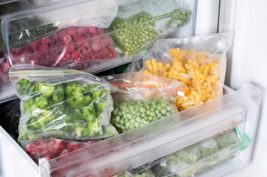 Buzdolabında farklı donmuş sebzeler olan plastik poşetler. Yiyecek deposu