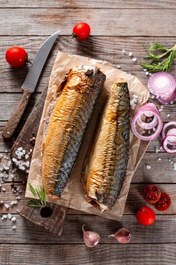 Delicious smoked mackerel on a wooden board on dark rustic background. Top view. clipart
