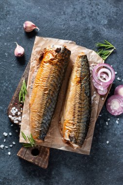 Baharatlı, biberli ve sebzeli füme balığı kara taş arka planda el işi kağıdında görmek. Akdeniz yemeği, ringa balığı, deniz ürünleri, üst manzara.