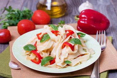 Kırmızı biber ve fesleğen ahşap masa üzerinde bir kase ile makarna