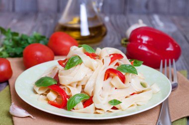 Kırmızı biber ve fesleğen ahşap masa üzerinde bir kase ile makarna