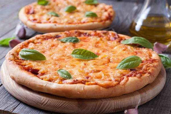 Pizza with cheese and basil on a wooden board — Stock Photo, Image