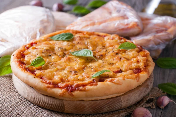 Pizza with cheese and basil on a wooden board — Stock Photo, Image