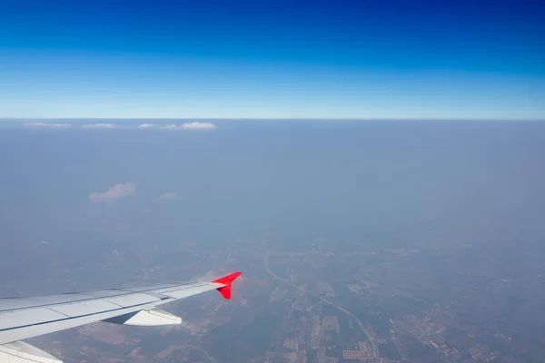 Gökyüzünde bir uçak kanadı Gökyüzü atmosferi bulutlu ve toz kalın. Asya kıtasına uç, Tayland.