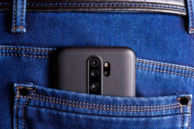 Kot pantolonun arka cebinde akıllı telefon.