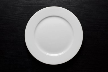 Yuvarlak, beyaz, siyah ahşap arka planda boş bir tabak.