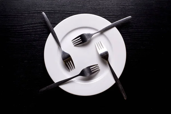 Πιρούνια Τοποθετούνται Ένα Σταυρό Λευκό Στρογγυλό Πιάτο Ένα Άδειο Πιάτο — Φωτογραφία Αρχείου