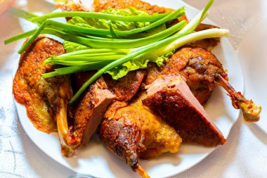 Pişmiş ördek. Yeşil soğan ve marullu tabakta ördek rostosu. Kutlama masası