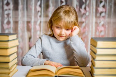 Uzaktan öğrenme. Düşünceli bakışlı okul kızı bir kitap okuyor. Ödev yapan öğrenci