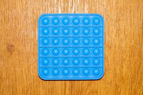 Pop it. A popular sensory anti-stress toy, pop it on a wooden surface.