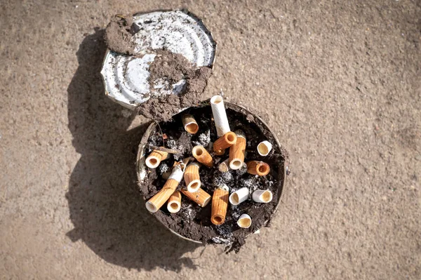 Cigarette butts in an old dirty tin can. Smoking is a bad habit that many people fall ill with. Concept of a life-threatening habit, damage to the lungs and respiratory tract.